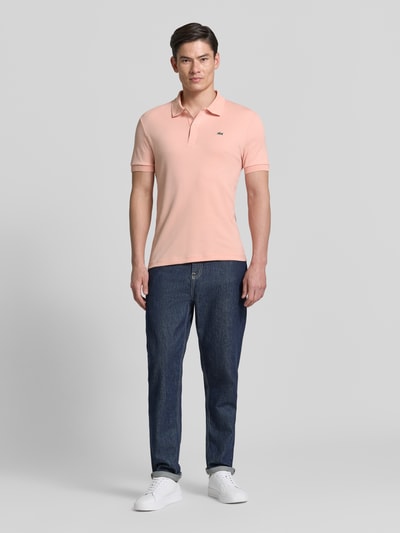 Männermodel trägt Regular Fit Poloshirt aus reiner Baumwolle von Lacoste, Optik: Unifarben, Logo-Detail, Ganzkörperansicht von vorne.