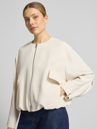 Modelka kobieca nosi Boxy Fit Blouson mit Zweiwege-Reißverschluss Modell 'JAJILA' od BOSS, kremowa twillowa tkanina, ozdobne kieszenie, widok na górną część ciała z przodu.