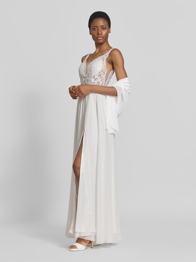 Frauenmodel trägt Brautkleid mit floralem Stitching von Mascara, kwiatowy haft, taliowany krój, dekolt w serek, półprzezroczysty materiał, bez rękawów, długość tyłu w rozmiarze 36: 135 cm, szerokość w rozmiarze 36: 34 cm, jasne barwy, miękkie tkaniny, cała sylwetka z przodu.