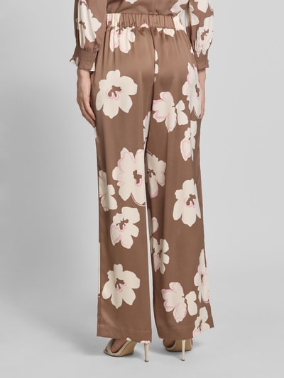 Frauenmodel trägt Loose Fit Satinhose mit Allover-Muster von s.Oliver BLACK LABEL in Braun mit floralem Muster, Satin-Materialverarbeitung, Ganzkörperansicht Rückansicht.