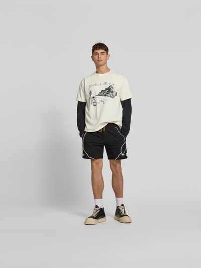 Männermodel trägt Shorts mit Label-Stitching von RHUDE in Schwarz mit weißem Stitching, elastischer Bund, Eingrifftaschen, Ganzkörperansicht von vorne.