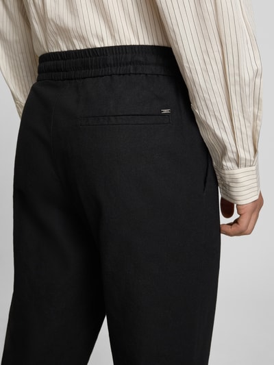 Männermodel trägt Tapered Leinenhose aus Baumwoll-Leinen-Mix Modell 'LINUS' von Only & Sons in Melange-Optik mit elastischem Bund, Gesäßtasche, Ganzkörperansicht Rückansicht.