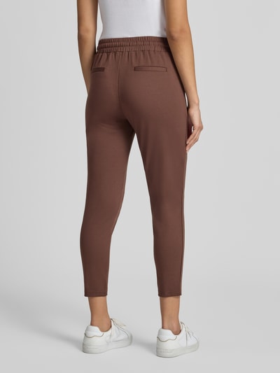 Frauenmodel trägt Slim Fit Hose mit Viskose-Anteil Modell 'KATE' von ICHI in Braun, elastischer Bund, verkürzte Passform, Ganzkörperansicht Rückansicht.