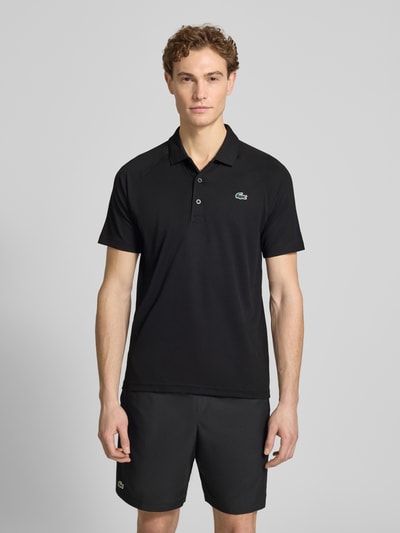 Männermodel trägt Regular Fit Sport Poloshirt mit Label Patch von Lacoste Sport in Schwarz, Piqué, unifarben, Ganzkörperansicht von vorne.