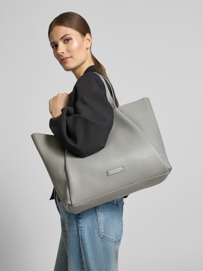 Frauenmodel trägt Shopper aus reinem Rindsleder von Marc O'Polo in Lederoptik mit Label-Patch, Tragehenkel, Hauptfach, Magnetverschluss, Ganzkörperansicht von vorne.