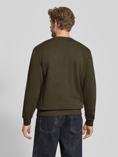 Męski model nosi Sweatshirt mit Label-Patch od Scotch & Soda z bawełny, luźny krój, okrągły dekolt, prążkowane wykończenia, długość tyłu w rozmiarze M: 64 cm, długość rękawów w rozmiarze M: 64 cm, cała sylwetka z tyłu