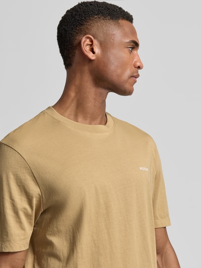 Männermodel trägt Regular Fit T-Shirt aus reiner Baumwolle Modell 'DERO222' von HUGO in Beige, unifarben, Rundhals, Nahaufnahme Oberkörper.