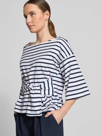 Frauenmodel trägt T-Shirt mit Knotendetail Modell 'DAJANA' von GUIDO MARIA KRETSCHMER WOMAN, Reine Baumwolle, taillierter Schnitt, Rundhalsausschnitt, 3/4-Arm, Rückenlänge 51 cm, Querstreifen in Weiß und Dunkelblau, Nahaufnahme Oberkörper.