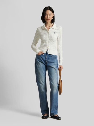 Frauenmodel trägt Slim Fit Strickjacke aus reiner Baumwolle von Polo Ralph Lauren, weiß, Zopfmuster, einfarbig, krój slim fit, Hemdblusenkragen, Logo-Stitching, einreihige Knopfleiste, Strick, langarm, gerippte Abschlüsse, Ganzkörperansicht von vorne