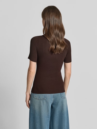 Frauenmodel trägt Slim Fit Poloshirt aus Rippstrick von BOSS in Dunkelbraun, feine Rippenstruktur, Polokragen, 3-Knopf-Verschluss, Ganzkörperansicht Rückansicht.