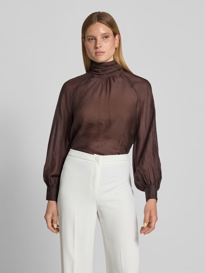 Frauenmodel trägt Regular Fit Bluse aus Viskose-Mix mit Stehkragen von Christian Berg Cocktail, semitransparent, braun, feine Struktur, lange Ärmel, eingefasste Ärmelabschlüsse, Ganzkörperansicht von vorne.