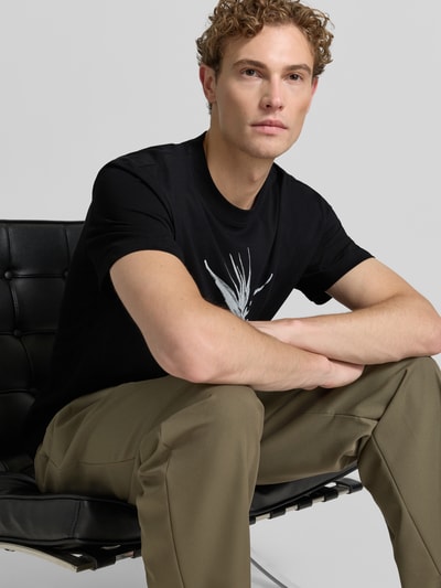 Männermodel trägt schwarzes Relaxed-Fit Herren T-Shirt aus reiner Baumwolle Modell 'DARISE' von HUGO, Nahaufnahme Oberkörper.