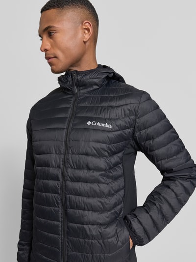 Männermodel trägt Gewatteerd jack met capuchon en logoprint van Columbia, regular fit, ritssluiting, ruglengte maat M 72 cm, schouderbreedte 47 cm, borstwijdte 52 cm, mouwlengte 69 cm, nahaufnahme bovenlichaam.