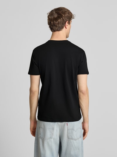 Męski model nosi czarny t-shirt z bawełny prosty krój, detal z logo, Alpha Industries, model 'Foam', długość tyłu 67 cm, całkowity widok od tyłu