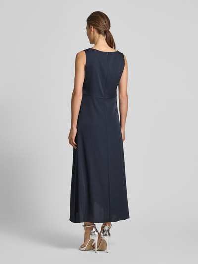 Frauenmodel trägt Cocktailkleid mit asymmetrischem Saum von Vera Mont in Dunkelblau, Taillierter Schnitt, Midikleid, U-Boot-Ausschnitt, Raffung an der Taille, rückseitiger Reißverschluss, Rückenlänge bei Größe 36: 128 cm, Brustweite bei Größe 36: 45 cm, Ganzkörperansicht Rückansicht.