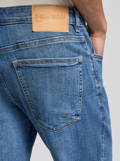 Männermodel trägt Slim Fit Jeans mit klassischem Five-Pocket-Design von REVIEW, blaue Waschung, Nahaufnahme Rückansicht, Baumwoll-Elasthan-Mix.