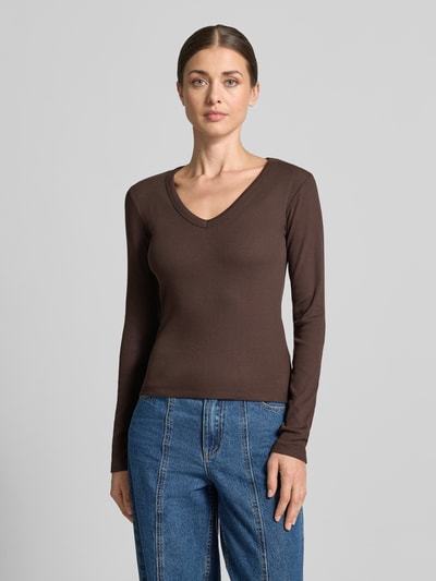 Frauenmodel trägt braunes Slim Fit Langarmshirt aus Baumwoll-Mix Modell 'CHLOE' von VERO MODA, kombiniert mit blauer Jeans, Ganzkörperansicht von vorne. Damen Langarmshirt von VERO MODA.
