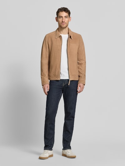 Mannenmodel draagt Lederjacke aus Schafsnubuk met ritssluiting model 'TRIVEN' van MAURITIUS in regular fit, platte kraag, ritszakken; nubuck van schapenleer in lichtbruin, jeans en sneakers; geheelopname vooraan.