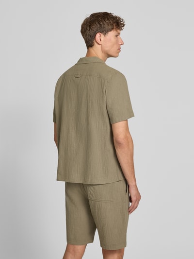 Männermodel trägt Resort Fit Freizeithemd aus reiner Baumwolle von s.Oliver RED LABEL in Khaki, strukturierte Oberfläche, Ganzkörperansicht Rückansicht.