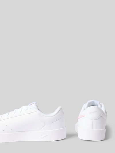 Produktfoto, Sneaker mit Logo-Detail von Nike in Weiß mit rosa Akzenten auf glatter Oberfläche, Damen Sneaker von Nike.