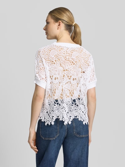 Frauenmodel trägt Strickshirt aus Spitze mit Rundhalsausschnitt von monari, weiße Baumwolle, Regular Fit, transparente Textur, Rückansicht Ganzkörperansicht.