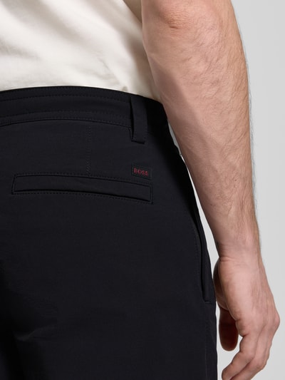 Männermodel trägt Straight Leg Chino mit Kordelzug Modell 'CHINO' von BOSS Oranje, effen kleuren, labelpatch, labelstitching, boord met tunnelkoord, achterzakken, zijritszak, detailaufnahme rechterschouder.