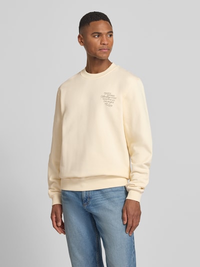 Männermodel trägt Sweatshirt mit rückseitigem Motiv-Print Modell 'Ben Faience' von Les Deux in Creme, Rundhalsausschnitt, Ganzkörperansicht von vorne
