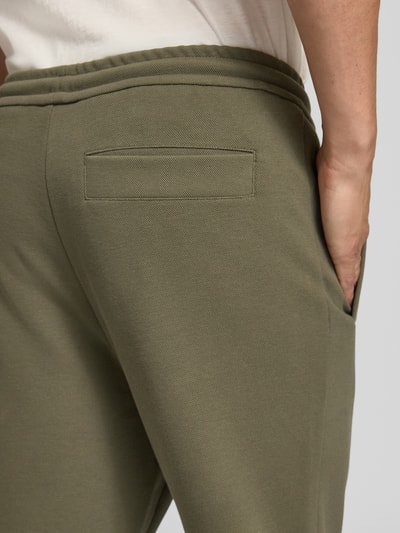 Männermodel trägt Regular Fit Sweathose aus Baumwoll-Mix Modell 'JT_Union Hadiko' von BOSS, olivegrün, strukturierte Oberfläche, Nahaufnahme Oberkörper, Herren Sweathose von BOSS