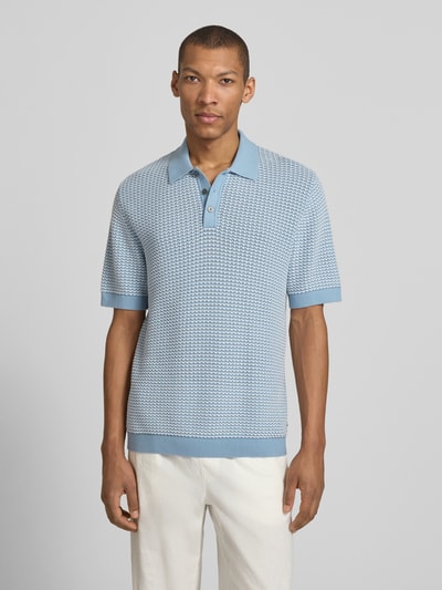 Męski model nosi Regular Fit Poloshirt in Strick-Optik Modell 'Kingsley' von Jack & Jones Premium z bawełny, krój regular fit, imitacja dzianiny, z krótkim rękawem, kołnierzyk polo, elastyczne wykończenia, długość tyłu w rozmiarze M: 77 cm, kolor jasnoniebieski i biały, faktura dzianiny, widok całej sylwetki z przodu.