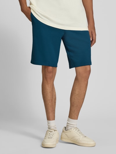 Männermodel trägt Shorts mit Logo und elastischem Bund von PUMA in Blau aus Baumwoll-Mix, Regular Fit, Nahaufnahme Unterkörper. Bundweite bei Größe M: 39 cm, Innenbeinlänge bei Größe M: 26 cm.