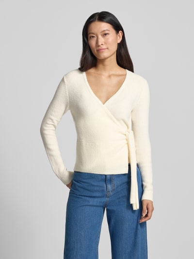 Frauenmodel trägt Regular Fit Wickeljacke mit Baumwoll-Anteil in Strick-Optik von Oui, cremefarben, langärmelig, V-Ausschnitt, elastischer Material-Mix, Ganzkörperansicht von vorne.