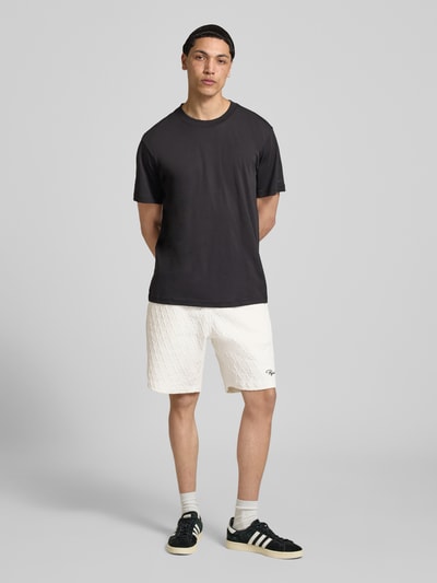 Męski model nosi białe Shorts mit Logo-Stitching Modell 'Jovren' od Pegador, bawełniany materiał, luźny krój, widok całej sylwetki z przodu.