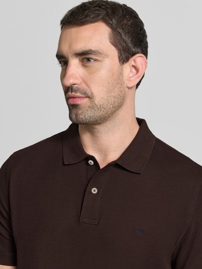 Männermodel trägt Regular Fit Poloshirt mit Label-Stitching von Fynch-Hatton in Dunkelbraun, reine Baumwolle, Nahaufnahme Oberkörper.