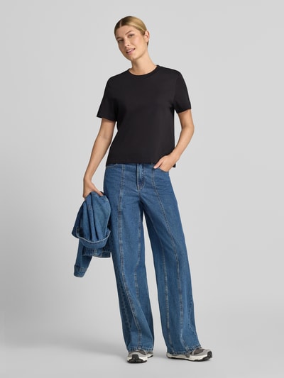 Frauenmodel trägt Regular Fit T-Shirt aus reiner Baumwolle von s.Oliver RED LABEL in Schwarz, kombiniert mit blauer Jeans, Ganzkörperansicht von vorne.
