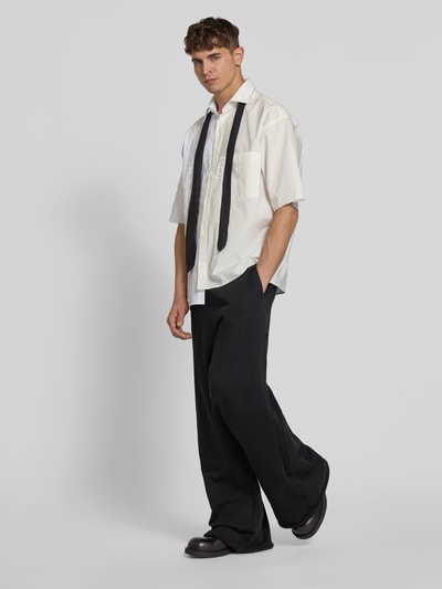 Männermodel trägt schwarze Derby-Schuhe mit Schnürverschluss von MM6 Maison Margiela, abgerundete Form, glatte Sohle, Ganzkörperansicht von vorne.
