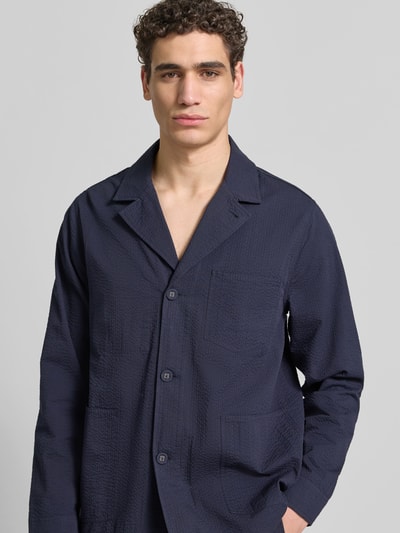 Männermodel trägt Relaxed Fit Hemdjacke aus Baumwolle von Officine Générale in Dunkelblau mit Knopfleiste, Brusttasche, Reverskragen, Nahaufnahme Oberkörper. Herren Hemdjacke, Reine Baumwolle, Rückenlänge bei Größe M: 74 cm.