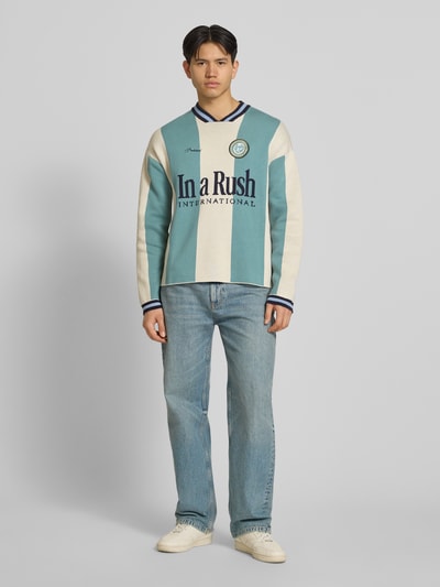 Männermodel trägt Strickpullover mit Label-Stitching Modell 'Overdrive' von PROHIBITED in Mint, Beige und Blau, reine Baumwolle, Relaxed Fit, Ganzkörperansicht von vorne.
