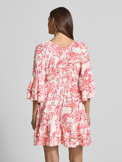 Frauenmodel trägt Minikleid aus Viskose mit V-Ausschnitt von Apricot, taillierter Schnitt, Allover-Look, florales Muster, Ganzkörperansicht Rückansicht.
