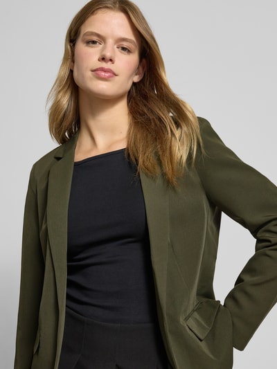 Kobiece model prezentuje Loose Fit Longblazer mit Abnähern Model 'BOZZY' od Pieces, efekt: jednolity kolor, krój loose fit, kołnierz z połami, długi rękaw, kieszenie z patką, bez zapięcia, wyhaftowane logo, zbliżenie na górną część sylwetki z przodu.