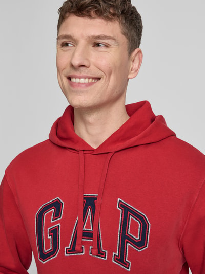 Mannenmodel draagt Hoodie met Logo en Kangoeroezak van GAP in rood, katoenmix, regular fit, logo, kangoeroezak, close-up bovenlichaam.