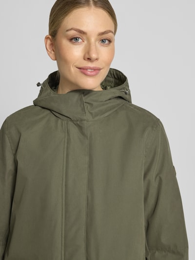 Frauenmodel trägt Parka mit Kapuze und Pattentaschen von camel active in Olivgrün, Baumwoll-Mix, Relaxed Fit, Nahaufnahme Oberkörper.