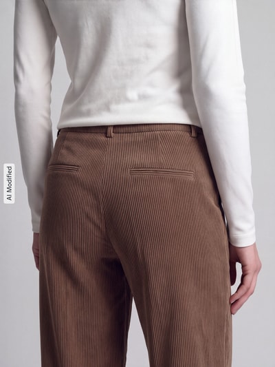 Frauenmodel trägt Relaxed Fit Cordhose seitliche Eingrifftaschen Modell 'ALEXIS' von CAMBIO, braun, feine Rippenstruktur, Nahaufnahme Rückansicht, KI-modifiziertes Bild.