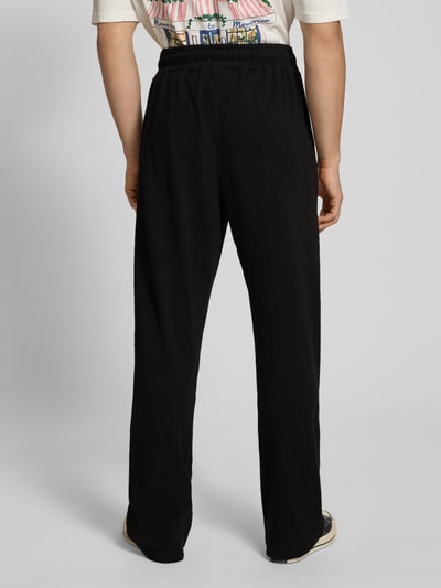 Männermodel trägt Loose Fit Sweathose mit Logo-Stitching Modell 'Signar' von Pegador aus reiner Baumwolle, schwarze Farbe, Ganzkörperansicht Rückansicht. Innenbeinlänge bei Größe M: 83 cm.