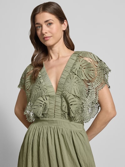 Vrouwenmodel draagt Midikleid met Loch-Stickerei Modell 'Cole' van Copenhagen Muse in lichtgroen, getailleerde fit, semi-transparant, modal-mix, detailopname bovenlichaam.