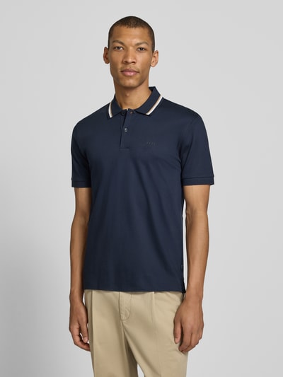 Männermodel trägt Slim Fit Poloshirt aus reiner Baumwolle Modell 'PENROSE' von BOSS, unifarben dunkelblau, Nahaufnahme Oberkörper.