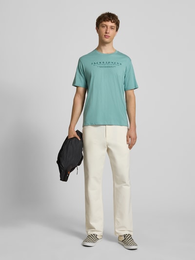 Männermodel trägt T-Shirt mit Logo und Rundhalsausschnitt von Jack & Jones, reine Baumwolle, Regular-Fit, Rückenlänge 71 cm, Ganzkörperansicht von vorne.