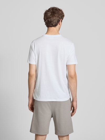 Männermodel trägt weißes T-Shirt mit Logo und Rundhalsausschnitt von CHAMPION, reine Baumwolle, Regular Fit, Rückansicht Ganzkörperansicht.
