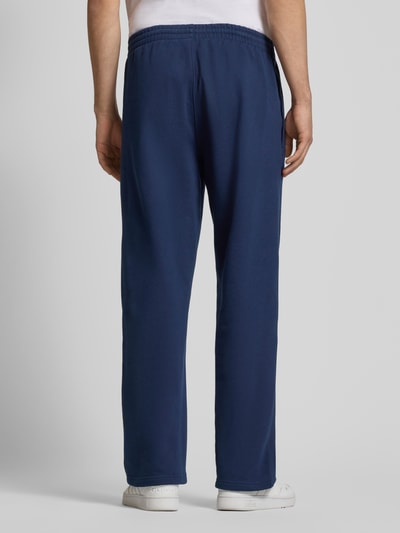 Männermodel trägt Wide Fit Sweatpants mit elastischem Bund von adidas Originals, dunkelblau, Baumwoll-Mix, Ganzkörperansicht Rückansicht.