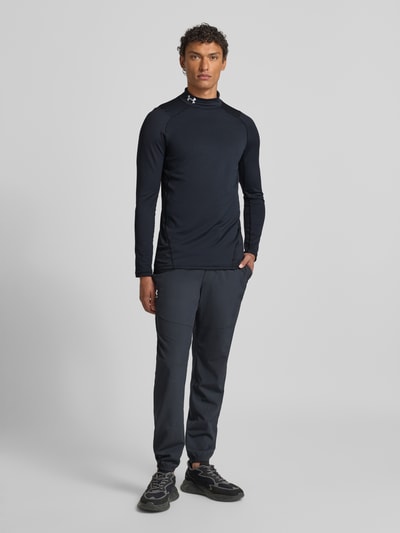 Männermodel trägt Longsleeve mit Stehkragen von Under Armour in Schwarz, Material-Mix mit Stretch-Anteil, Slim Fit, Ganzkörperansicht von vorne.