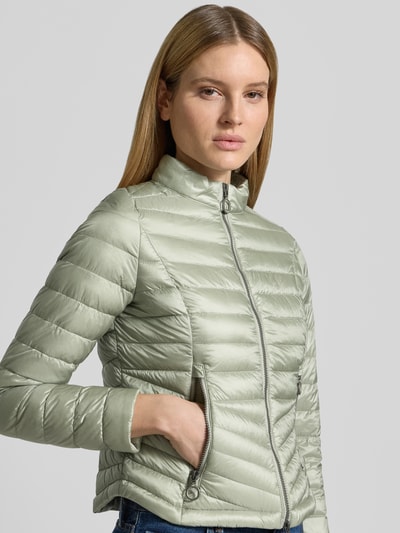 Frauenmodel trägt Steppjacke mit Stehkragen von Gil Bret in hellem Grün, mit Zweiwege-Reißverschluss, Reißverschlusstaschen, Körpernahe Passform, Ganzkörperansicht von vorne. Rückenlänge 56 cm, Schulterbreite 39 cm, Brustweite 47 cm, Ärmellänge 66 cm, Größe 36.